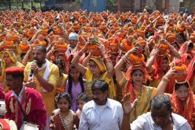 New Delhi, India July 25 2024 - Women with Kalash on head during Jagannath Temple Mangal Kalash Yatra, Indian Hindu devotees carry earthen pots containing sacred water with a coconut on top clipart