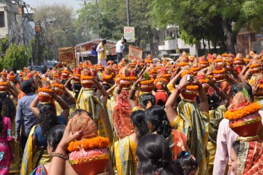 New Delhi, India July 25 2024 - Women with Kalash on head during Jagannath Temple Mangal Kalash Yatra, Indian Hindu devotees carry earthen pots containing sacred water with a coconut on top clipart