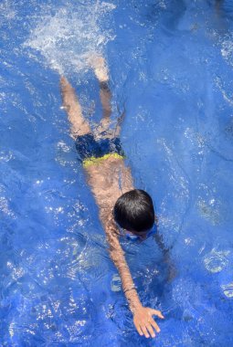 Havuzda yüzen mutlu Hintli çocuk, sıcak yaz tatillerinde hava tüpüyle birlikte yüzen çocuk, büyük bir havuzda yüzen çocuk..