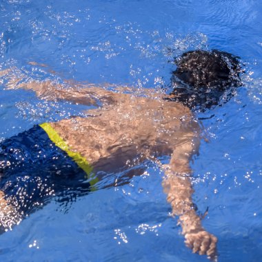 Havuzda yüzen mutlu Hintli çocuk, sıcak yaz tatillerinde hava tüpüyle birlikte yüzen çocuk, büyük bir havuzda yüzen çocuk..