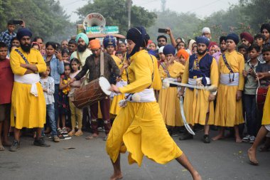 Delhi, Hindistan, 17 Kasım 2024 - Doğu Delhi bölgesinde Guru Nanak Dev, Nagar Kirtan 'ın doğum günü dolayısıyla geleneksel Nagar Kirtan, geleneksel Nagar geçit töreninde Sihler gatka ve dövüş sanatlarını sergiliyor
