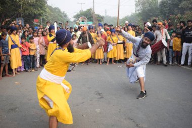 Delhi, Hindistan, 17 Kasım 2024 - Doğu Delhi bölgesinde Guru Nanak Dev, Nagar Kirtan 'ın doğum günü dolayısıyla geleneksel Nagar Kirtan, geleneksel Nagar geçit töreninde Sihler gatka ve dövüş sanatlarını sergiliyor