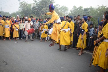 Delhi, Hindistan, 17 Kasım 2024 - Doğu Delhi bölgesinde Guru Nanak Dev, Nagar Kirtan 'ın doğum günü dolayısıyla geleneksel Nagar Kirtan, geleneksel Nagar geçit töreninde Sihler gatka ve dövüş sanatlarını sergiliyor