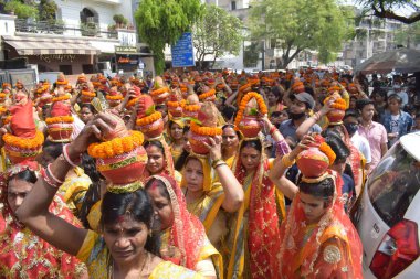 New Delhi, India July 25 2024 - Women with Kalash on head during Jagannath Temple Mangal Kalash Yatra, Indian Hindu devotees carry earthen pots containing sacred water with a coconut on top clipart