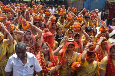 New Delhi, India July 25 2024 - Women with Kalash on head during Jagannath Temple Mangal Kalash Yatra, Indian Hindu devotees carry earthen pots containing sacred water with a coconut on top clipart