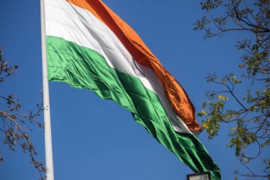 India flag flying high at Connaught Place with pride in blue sky, India flag fluttering, Indian Flag on Independence Day and Republic Day of India, tilt up shot, Waving Indian flag, Har Ghar Tiranga