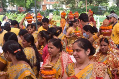 New Delhi, India July 25 2024 - Women with Kalash on head during Jagannath Temple Mangal Kalash Yatra, Indian Hindu devotees carry earthen pots containing sacred water with a coconut on top clipart