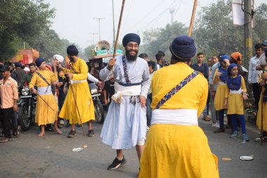 Delhi, Hindistan, 17 Kasım 2024 - Doğu Delhi bölgesinde Guru Nanak Dev, Nagar Kirtan 'ın doğum günü dolayısıyla geleneksel Nagar Kirtan, geleneksel Nagar geçit töreninde Sihler gatka ve dövüş sanatlarını sergiliyor