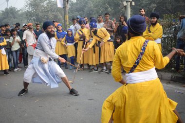 Delhi, Hindistan, 17 Kasım 2024 - Doğu Delhi bölgesinde Guru Nanak Dev, Nagar Kirtan 'ın doğum günü dolayısıyla geleneksel Nagar Kirtan, geleneksel Nagar geçit töreninde Sihler gatka ve dövüş sanatlarını sergiliyor