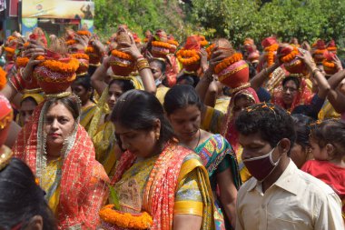 New Delhi, India July 25 2024 - Women with Kalash on head during Jagannath Temple Mangal Kalash Yatra, Indian Hindu devotees carry earthen pots containing sacred water with a coconut on top clipart