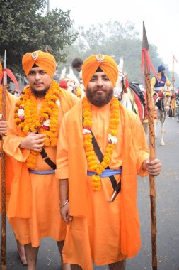 Delhi, Hindistan, 17 Kasım 2024 - Doğu Delhi bölgesinde Guru Nanak Dev, Nagar Kirtan 'ın doğum günü dolayısıyla geleneksel Nagar Kirtan, geleneksel Nagar geçit töreninde Sihler gatka ve dövüş sanatlarını sergiliyor