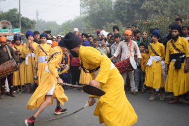 Delhi, Hindistan, 17 Kasım 2024 - Doğu Delhi bölgesinde Guru Nanak Dev, Nagar Kirtan 'ın doğum günü dolayısıyla geleneksel Nagar Kirtan, geleneksel Nagar geçit töreninde Sihler gatka ve dövüş sanatlarını sergiliyor