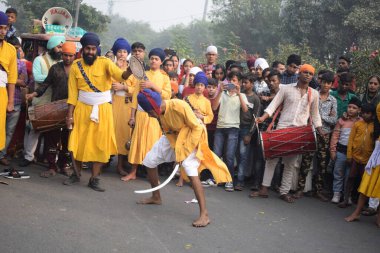 Delhi, Hindistan, 17 Kasım 2024 - Doğu Delhi bölgesinde Guru Nanak Dev, Nagar Kirtan 'ın doğum günü dolayısıyla geleneksel Nagar Kirtan, geleneksel Nagar geçit töreninde Sihler gatka ve dövüş sanatlarını sergiliyor