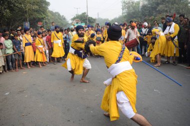 Delhi, Hindistan, 17 Kasım 2024 - Doğu Delhi bölgesinde Guru Nanak Dev, Nagar Kirtan 'ın doğum günü dolayısıyla geleneksel Nagar Kirtan, geleneksel Nagar geçit töreninde Sihler gatka ve dövüş sanatlarını sergiliyor