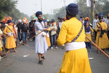 Delhi, Hindistan, 17 Kasım 2024 - Doğu Delhi bölgesinde Guru Nanak Dev, Nagar Kirtan 'ın doğum günü dolayısıyla geleneksel Nagar Kirtan, geleneksel Nagar geçit töreninde Sihler gatka ve dövüş sanatlarını sergiliyor