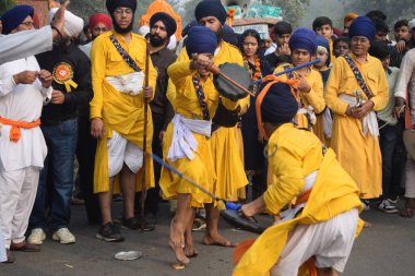 Delhi, Hindistan, 17 Kasım 2024 - Doğu Delhi bölgesinde Guru Nanak Dev, Nagar Kirtan 'ın doğum günü dolayısıyla geleneksel Nagar Kirtan, geleneksel Nagar geçit töreninde Sihler gatka ve dövüş sanatlarını sergiliyor