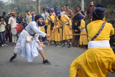 Delhi, Hindistan, 17 Kasım 2024 - Doğu Delhi bölgesinde Guru Nanak Dev, Nagar Kirtan 'ın doğum günü dolayısıyla geleneksel Nagar Kirtan, geleneksel Nagar geçit töreninde Sihler gatka ve dövüş sanatlarını sergiliyor