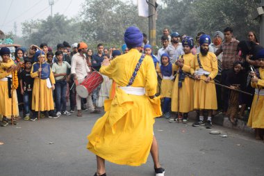 Delhi, Hindistan, 17 Kasım 2024 - Doğu Delhi bölgesinde Guru Nanak Dev, Nagar Kirtan 'ın doğum günü dolayısıyla geleneksel Nagar Kirtan, geleneksel Nagar geçit töreninde Sihler gatka ve dövüş sanatlarını sergiliyor