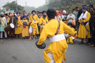 Delhi, Hindistan, 17 Kasım 2024 - Doğu Delhi bölgesinde Guru Nanak Dev, Nagar Kirtan 'ın doğum günü dolayısıyla geleneksel Nagar Kirtan, geleneksel Nagar geçit töreninde Sihler gatka ve dövüş sanatlarını sergiliyor