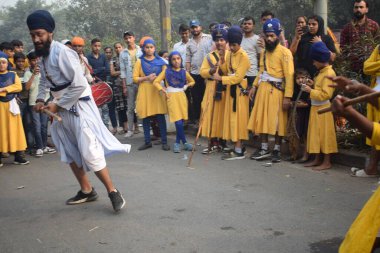 Delhi, Hindistan, 17 Kasım 2024 - Doğu Delhi bölgesinde Guru Nanak Dev, Nagar Kirtan 'ın doğum günü dolayısıyla geleneksel Nagar Kirtan, geleneksel Nagar geçit töreninde Sihler gatka ve dövüş sanatlarını sergiliyor
