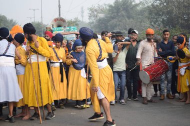 Delhi, Hindistan, 17 Kasım 2024 - Doğu Delhi bölgesinde Guru Nanak Dev, Nagar Kirtan 'ın doğum günü dolayısıyla geleneksel Nagar Kirtan, geleneksel Nagar geçit töreninde Sihler gatka ve dövüş sanatlarını sergiliyor
