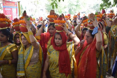 New Delhi, India July 25 2024 - Women with Kalash on head during Jagannath Temple Mangal Kalash Yatra, Indian Hindu devotees carry earthen pots containing sacred water with a coconut on top clipart