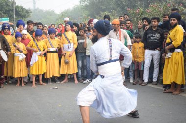 Delhi, Hindistan, 17 Kasım 2024 - Doğu Delhi bölgesinde Guru Nanak Dev, Nagar Kirtan 'ın doğum günü dolayısıyla geleneksel Nagar Kirtan, geleneksel Nagar geçit töreninde Sihler gatka ve dövüş sanatlarını sergiliyor