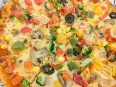 Biberli pizza tahtada, lezzetli ve çıtır vejetaryen pizzanın üst görüntüsü açık kahverengi masa arkasında Margherita.