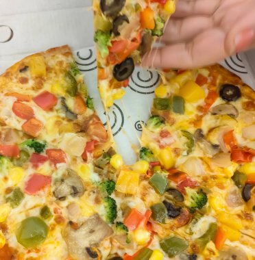 Biberli pizza tahtada, lezzetli ve çıtır vejetaryen pizzanın üst görüntüsü açık kahverengi masa arkasında Margherita.