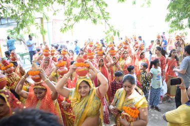 New Delhi, India July 25 2024 - Women with Kalash on head during Jagannath Temple Mangal Kalash Yatra, Indian Hindu devotees carry earthen pots containing sacred water with a coconut on top clipart