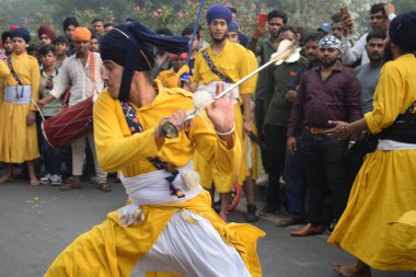 Delhi, Hindistan, 17 Kasım 2024 - Doğu Delhi bölgesinde Guru Nanak Dev, Nagar Kirtan 'ın doğum günü dolayısıyla geleneksel Nagar Kirtan, geleneksel Nagar geçit töreninde Sihler gatka ve dövüş sanatlarını sergiliyor