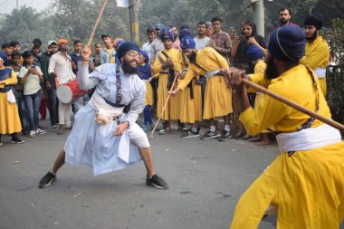 Delhi, Hindistan, 17 Kasım 2024 - Doğu Delhi bölgesinde Guru Nanak Dev, Nagar Kirtan 'ın doğum günü dolayısıyla geleneksel Nagar Kirtan, geleneksel Nagar geçit töreninde Sihler gatka ve dövüş sanatlarını sergiliyor