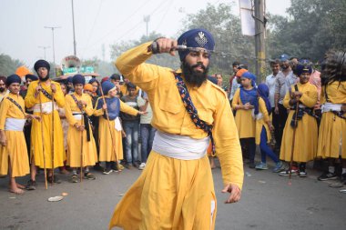 Delhi, Hindistan, 17 Kasım 2024 - Doğu Delhi bölgesinde Guru Nanak Dev, Nagar Kirtan 'ın doğum günü dolayısıyla geleneksel Nagar Kirtan, geleneksel Nagar geçit töreninde Sihler gatka ve dövüş sanatlarını sergiliyor