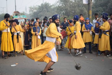 Delhi, Hindistan, 17 Kasım 2024 - Doğu Delhi bölgesinde Guru Nanak Dev, Nagar Kirtan 'ın doğum günü dolayısıyla geleneksel Nagar Kirtan, geleneksel Nagar geçit töreninde Sihler gatka ve dövüş sanatlarını sergiliyor