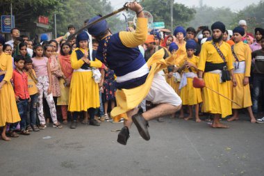 Delhi, Hindistan, 17 Kasım 2024 - Doğu Delhi bölgesinde Guru Nanak Dev, Nagar Kirtan 'ın doğum günü dolayısıyla geleneksel Nagar Kirtan, geleneksel Nagar geçit töreninde Sihler gatka ve dövüş sanatlarını sergiliyor