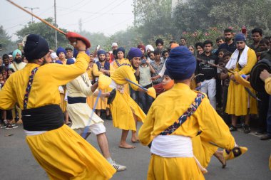 Delhi, Hindistan, 17 Kasım 2024 - Doğu Delhi bölgesinde Guru Nanak Dev, Nagar Kirtan 'ın doğum günü dolayısıyla geleneksel Nagar Kirtan, geleneksel Nagar geçit töreninde Sihler gatka ve dövüş sanatlarını sergiliyor