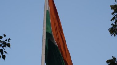 India flag flying high at Connaught Place with pride in blue sky, India flag fluttering, Indian Flag on Independence Day and Republic Day of India, tilt up shot, Waving Indian flag, Har Ghar Tiranga