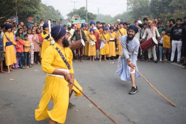 Delhi, Hindistan, 17 Kasım 2024 - Doğu Delhi bölgesinde Guru Nanak Dev, Nagar Kirtan 'ın doğum günü dolayısıyla geleneksel Nagar Kirtan, geleneksel Nagar geçit töreninde Sihler gatka ve dövüş sanatlarını sergiliyor