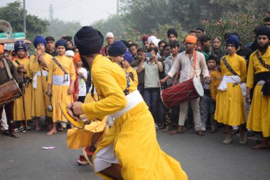 Delhi, Hindistan, 17 Kasım 2024 - Doğu Delhi bölgesinde Guru Nanak Dev, Nagar Kirtan 'ın doğum günü dolayısıyla geleneksel Nagar Kirtan, geleneksel Nagar geçit töreninde Sihler gatka ve dövüş sanatlarını sergiliyor