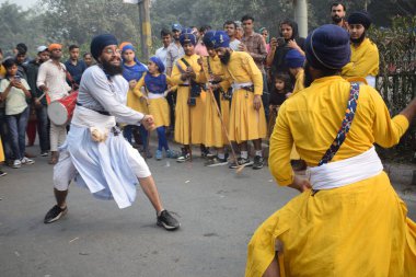 Delhi, Hindistan, 17 Kasım 2024 - Doğu Delhi bölgesinde Guru Nanak Dev, Nagar Kirtan 'ın doğum günü dolayısıyla geleneksel Nagar Kirtan, geleneksel Nagar geçit töreninde Sihler gatka ve dövüş sanatlarını sergiliyor