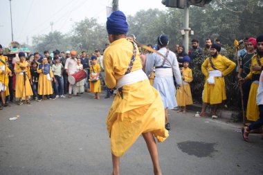 Delhi, Hindistan, 17 Kasım 2024 - Doğu Delhi bölgesinde Guru Nanak Dev, Nagar Kirtan 'ın doğum günü dolayısıyla geleneksel Nagar Kirtan, geleneksel Nagar geçit töreninde Sihler gatka ve dövüş sanatlarını sergiliyor