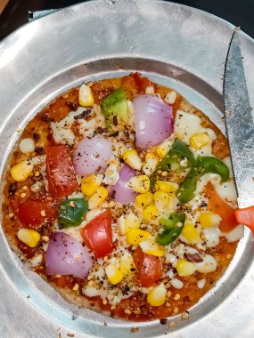 Biberli pizza tahtada, lezzetli ve çıtır vejetaryen pizzanın üst görüntüsü açık kahverengi masa arkasında Margherita.