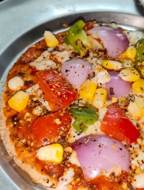 Biberli pizza tahtada, lezzetli ve çıtır vejetaryen pizzanın üst görüntüsü açık kahverengi masa arkasında Margherita.