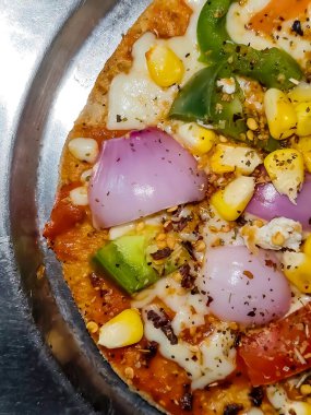 Biberli pizza tahtada, lezzetli ve çıtır vejetaryen pizzanın üst görüntüsü açık kahverengi masa arkasında Margherita.