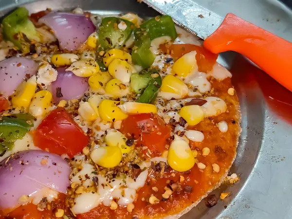 Biberli pizza tahtada, lezzetli ve çıtır vejetaryen pizzanın üst görüntüsü açık kahverengi masa arkasında Margherita.