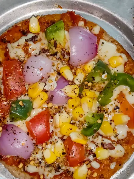 Biberli pizza tahtada, lezzetli ve çıtır vejetaryen pizzanın üst görüntüsü açık kahverengi masa arkasında Margherita.