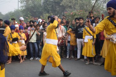 Delhi, Hindistan, 17 Kasım 2024 - Doğu Delhi bölgesinde Guru Nanak Dev, Nagar Kirtan 'ın doğum günü dolayısıyla geleneksel Nagar Kirtan, geleneksel Nagar geçit töreninde Sihler gatka ve dövüş sanatlarını sergiliyor