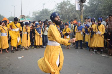 Delhi, Hindistan, 17 Kasım 2024 - Doğu Delhi bölgesinde Guru Nanak Dev, Nagar Kirtan 'ın doğum günü dolayısıyla geleneksel Nagar Kirtan, geleneksel Nagar geçit töreninde Sihler gatka ve dövüş sanatlarını sergiliyor