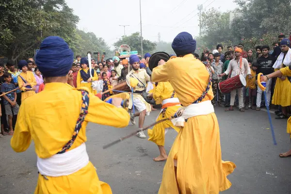 Delhi, Hindistan, 17 Kasım 2024 - Doğu Delhi bölgesinde Guru Nanak Dev, Nagar Kirtan 'ın doğum günü dolayısıyla geleneksel Nagar Kirtan, geleneksel Nagar geçit töreninde Sihler gatka ve dövüş sanatlarını sergiliyor