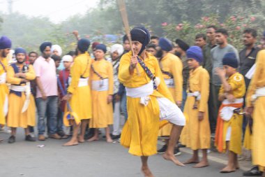Delhi, Hindistan, 17 Kasım 2024 - Doğu Delhi bölgesinde Guru Nanak Dev, Nagar Kirtan 'ın doğum günü dolayısıyla geleneksel Nagar Kirtan, geleneksel Nagar geçit töreninde Sihler gatka ve dövüş sanatlarını sergiliyor